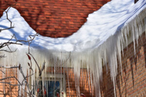 snow sits on the edge of a red roof with icicles hanging down