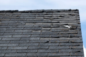 A black roof shows curling and missing shingles, signs of age