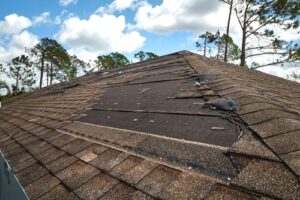 wind damaged roof shows missing shingles on a sunny day