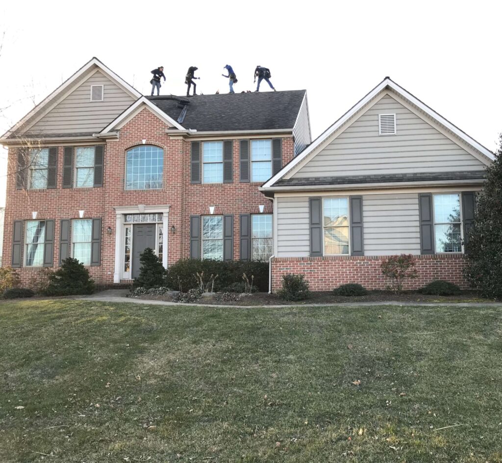 Our home exterior specialists work on the roof of a brick home