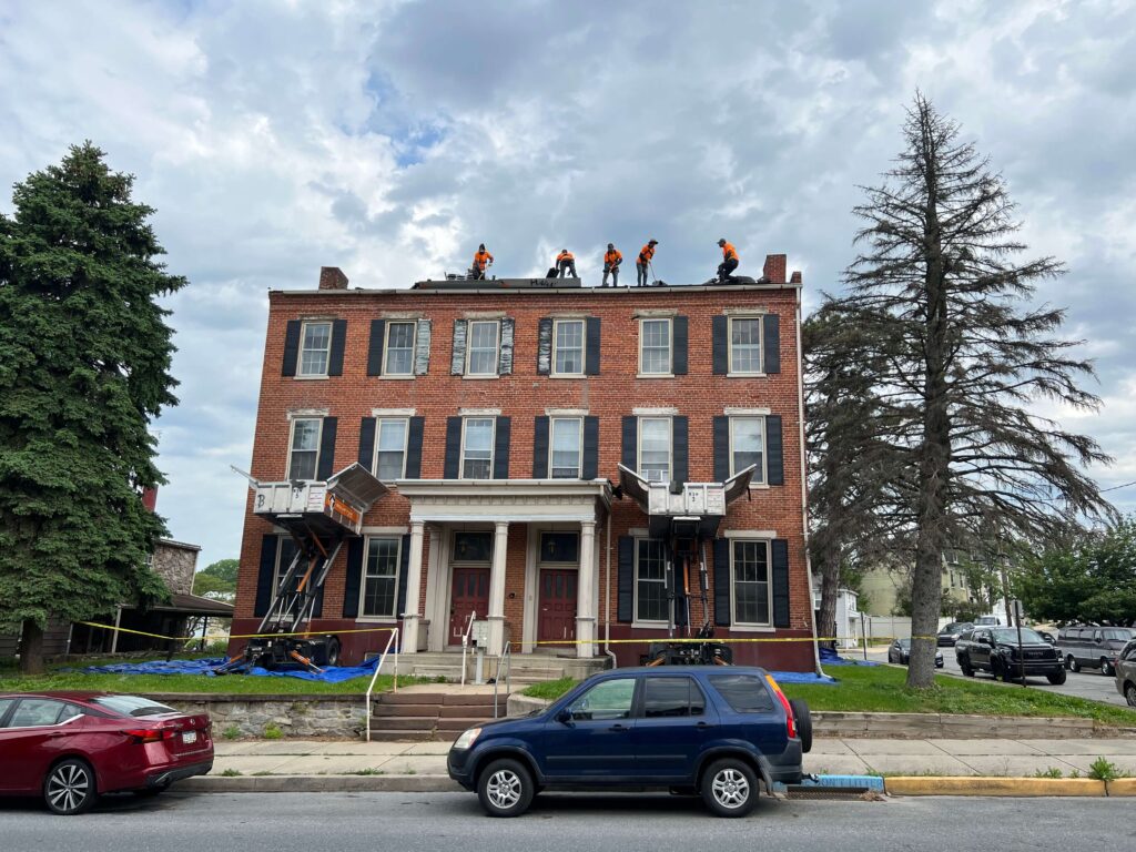 crews work on the roof of a brick building