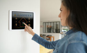 A woman touches a screen on the wall of her home that controls the thermostat