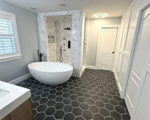 A bathroom with black tiled floor and a white tub