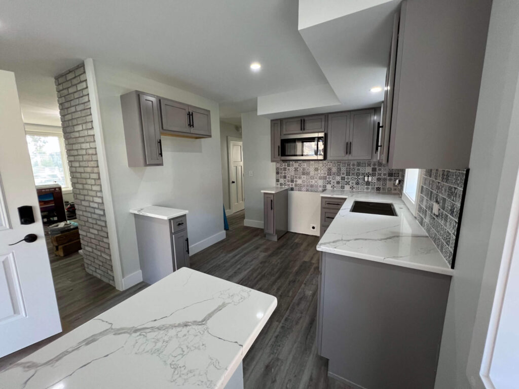 An expert kitchen remodel with gray cabinets and a gray backsplash.